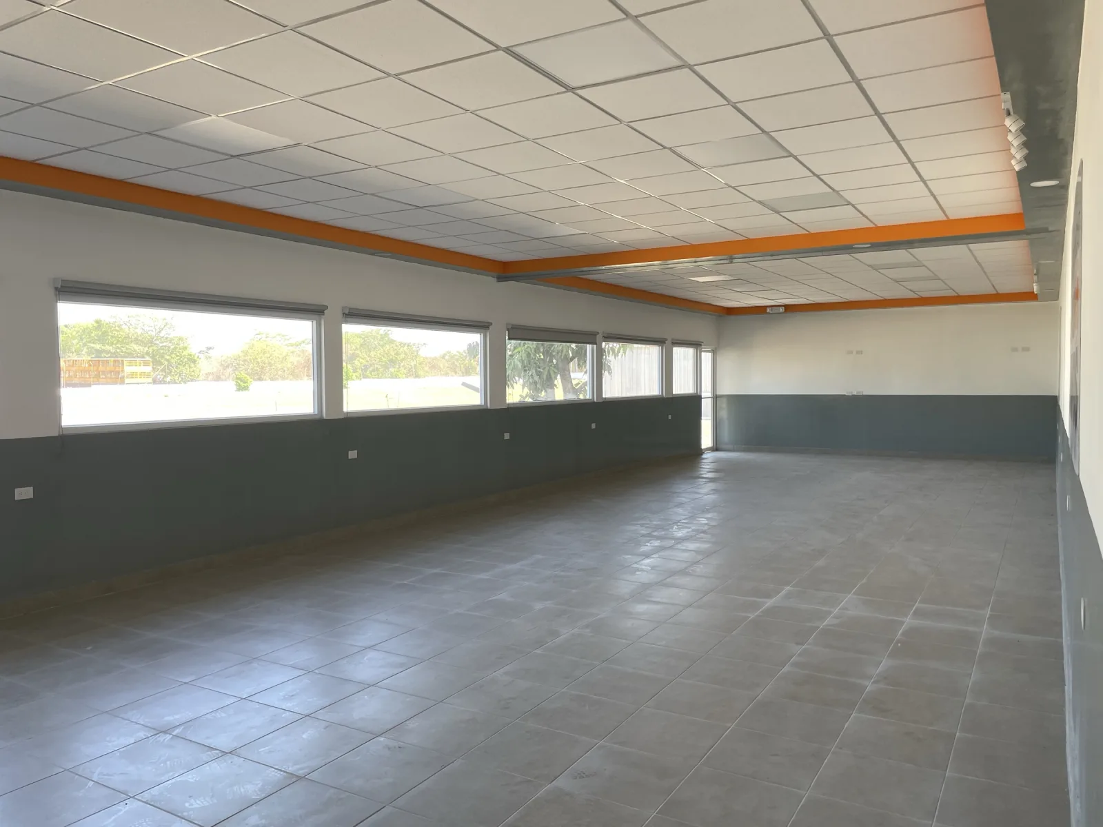 Comedor de nueva construcción con ventanería corrida y cielo falso con detalle naranja.